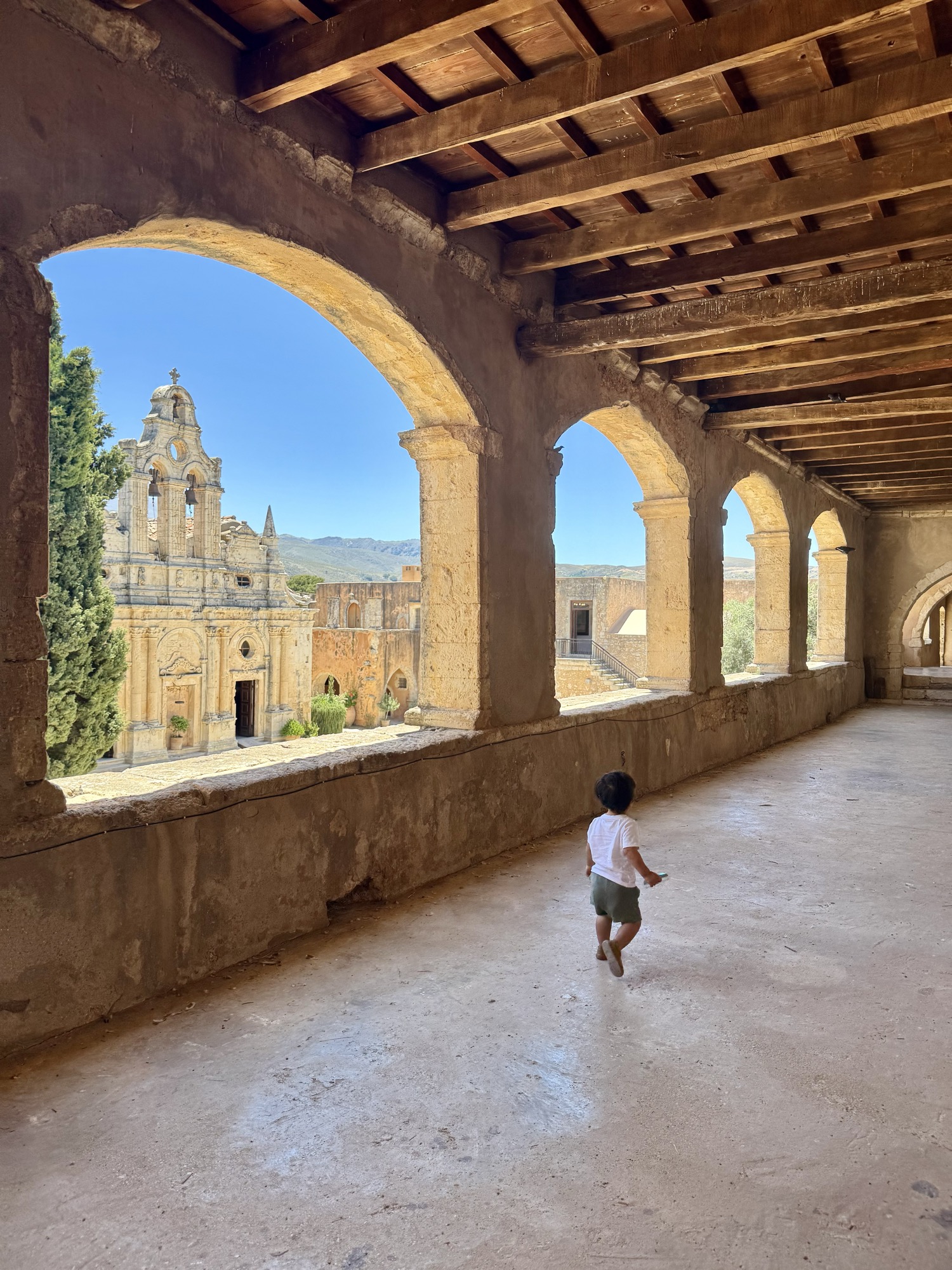 A child walking through the arched colonnade at Arkadi Monastery, Crete